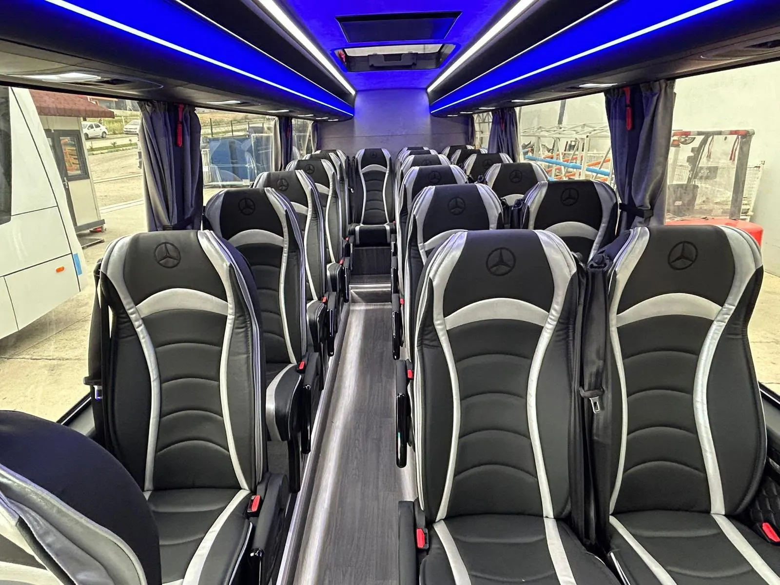 Innenraum eines Cars mit blauer LED-Deckenbeleuchtung und Sitzen mit Mercedes-Logo