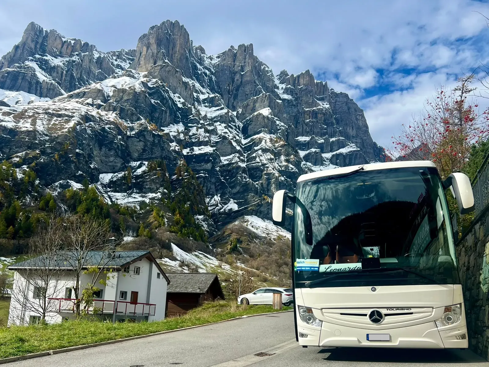 Autocarro da Leonardo Travel numa aldeia dos Alpes suíços, com montanhas nevadas ao fundo